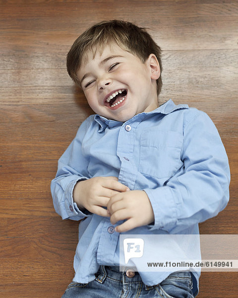 Laughing Caucasian boy laying on floor