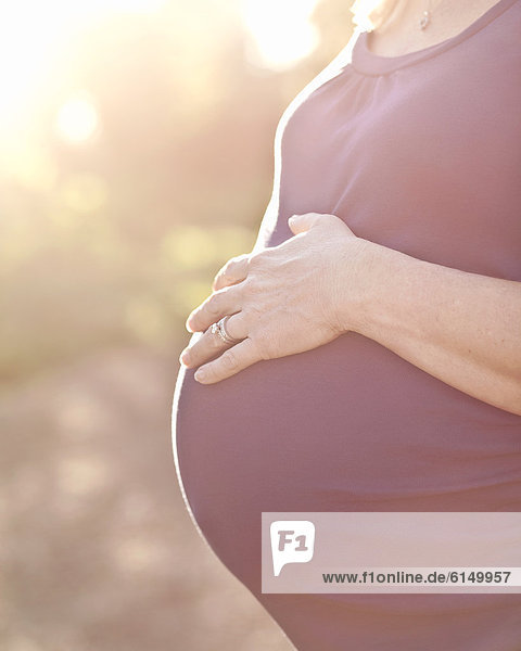Pregnant Caucasian woman caressing stomach