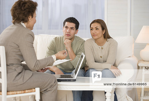 Hispanic businesswoman talking to couple in home