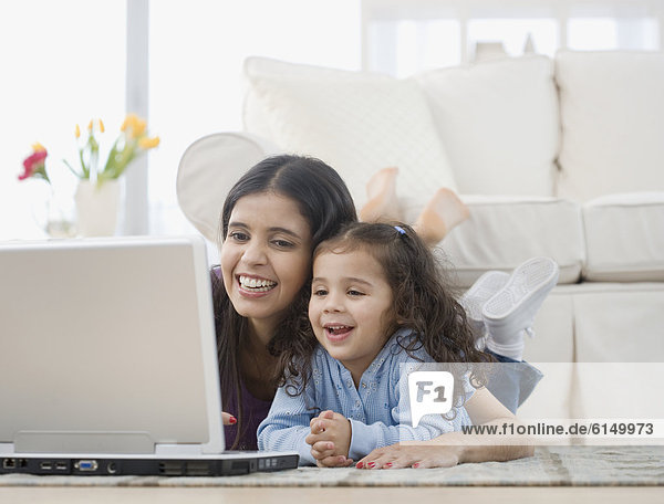Hispanic mother and daughter looking at laptop