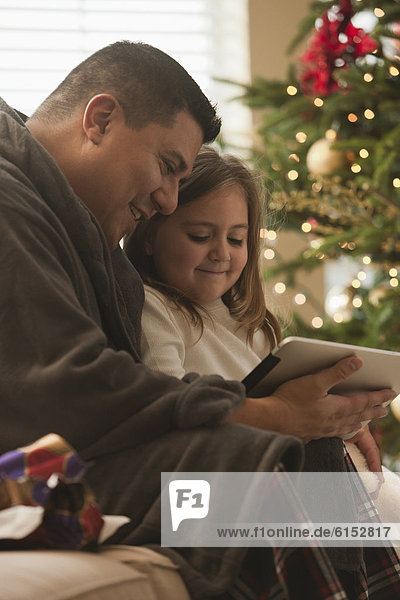Father and daughter looking at digital tablet on Christmas morning