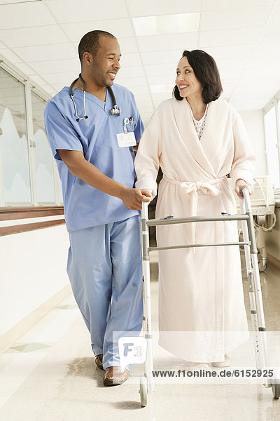 Nurse helping patient use walker in hospital