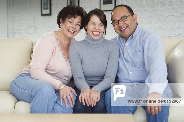 Hispanic parents and adult daughter on sofa