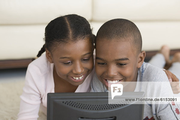 African brother and sister looking at laptop