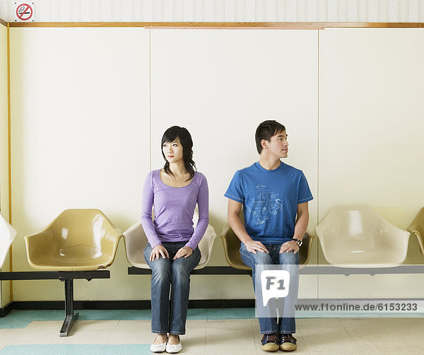 Asian couple sitting in waiting area