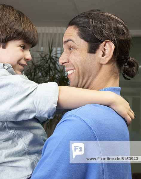 Hispanic father and son smiling at each other