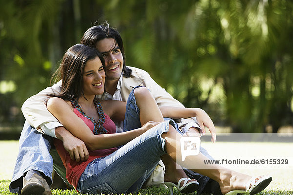 South American couple sitting on grass