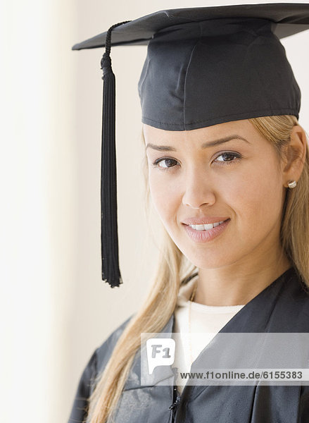 Young Hispanic woman wearing graduation cap and gown