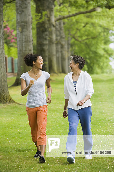 African American mother and adult daughter walking in park