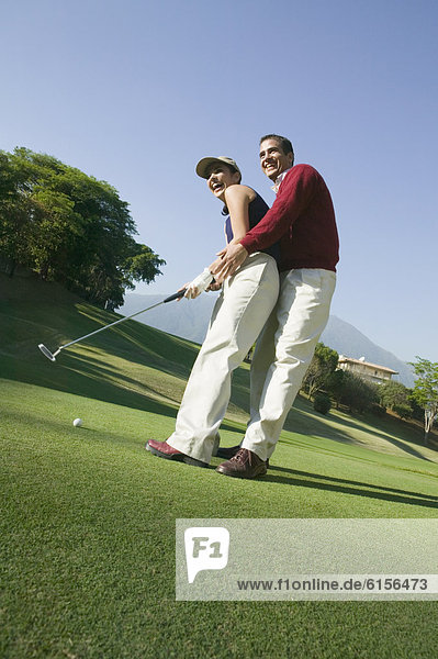 Hispanic couple playing golf
