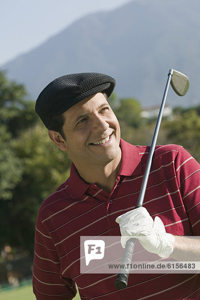 Hispanic man holding golf club over shoulder