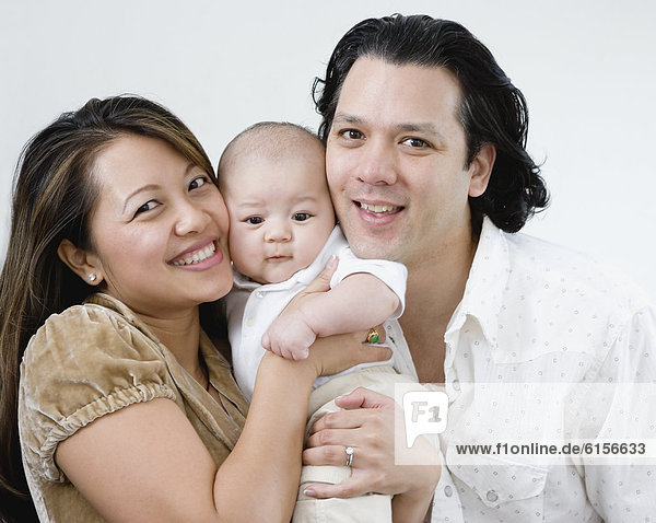 Asian parents hugging baby