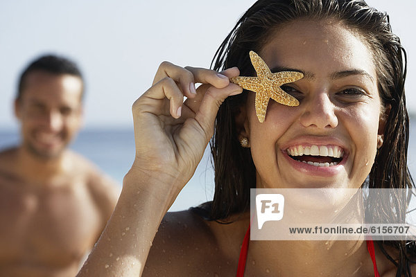 South American woman holding starfish over eye