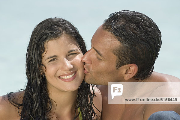 Hispanic man kissing girlfriend on cheek
