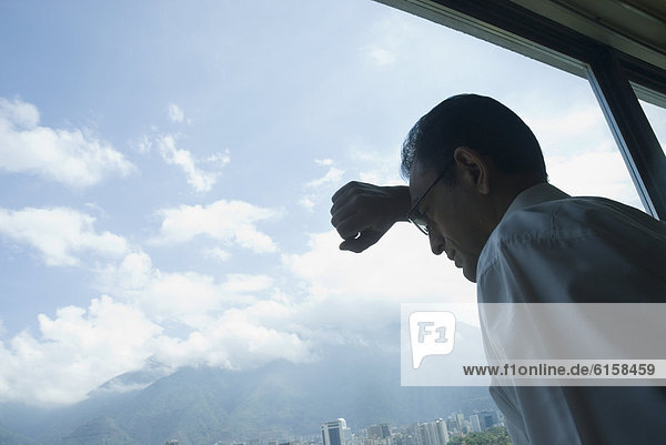 Hispanic businessman looking out window