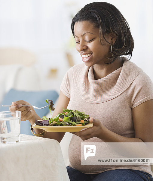 Pregnant African American woman eating salad