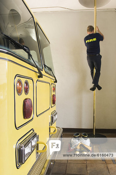 Male firefighter sliding down pole