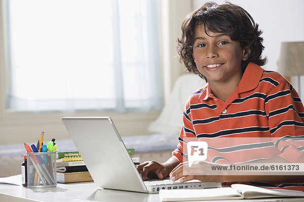 Mixed Race boy typing on laptop