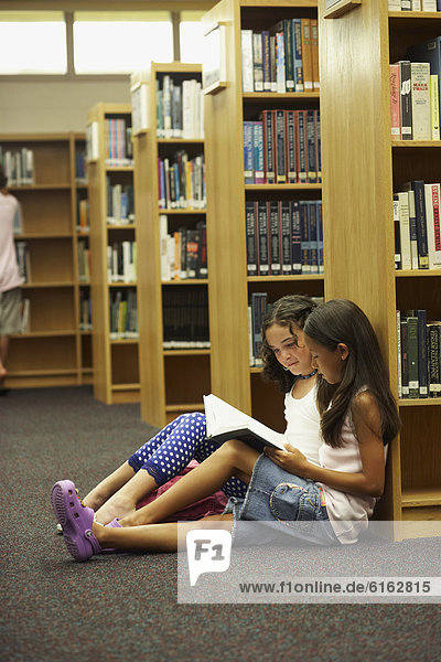Multi-ethnic students reading library book