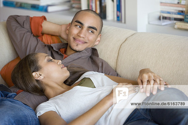 African American couple laying on sofa