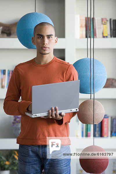 African American man holding laptop