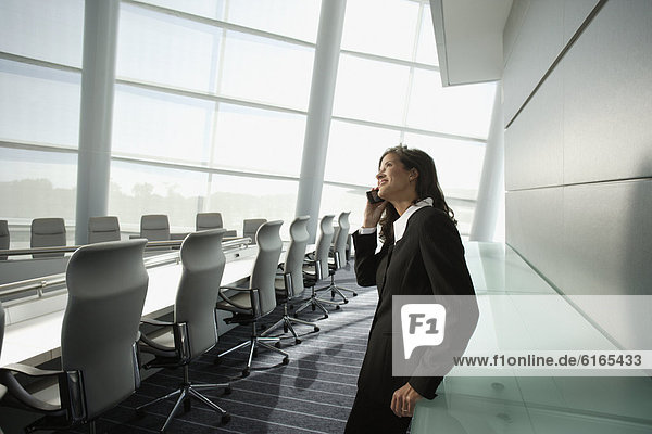 Businesswoman talking on cell phone in conference room