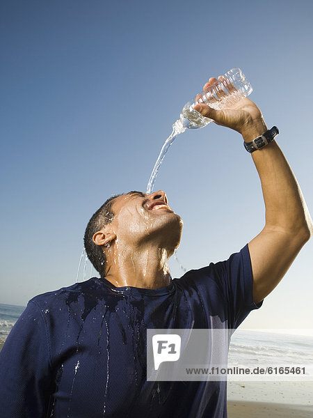 Hispanic man pouring water over head