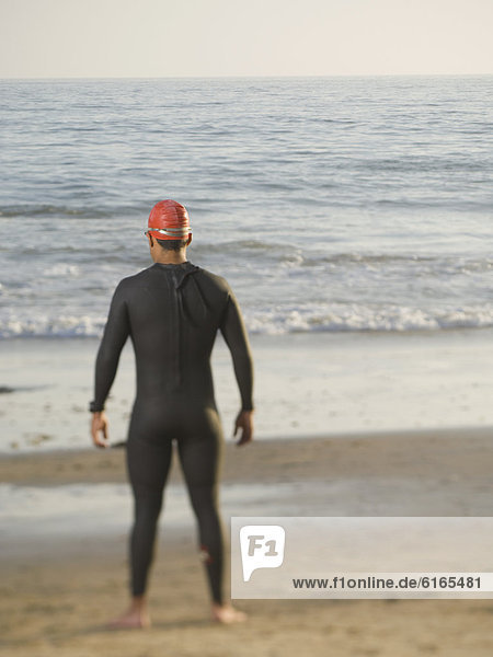Rear view of Hispanic man wearing wetsuit