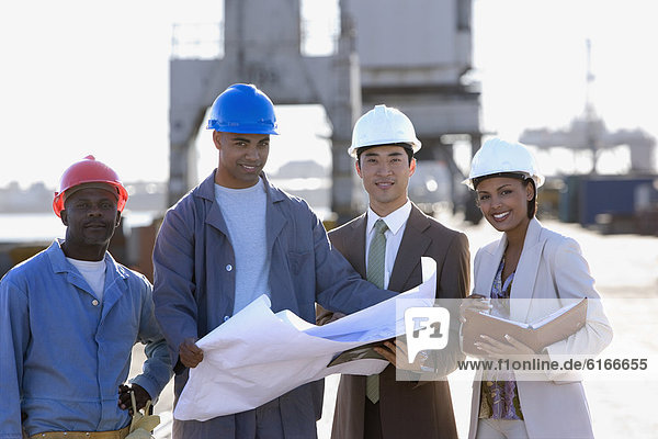 Multi-ethnic businesspeople and construction workers with blueprints