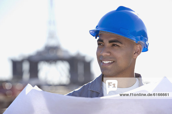 African American male construction worker holding blueprints
