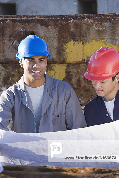 Multi-ethnic male construction workers holding blueprints