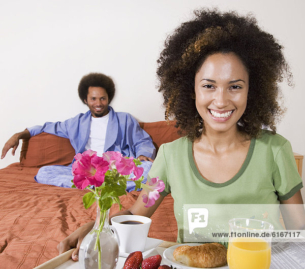 African woman carrying breakfast in bed tray
