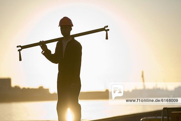Asian male dock worker holding pipe