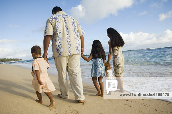 Pacific Islander family walking on beach