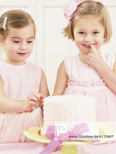 Young girls picking at a birthday cake