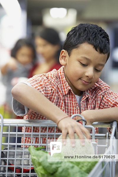 Indian boy putting fruit in shopping cart