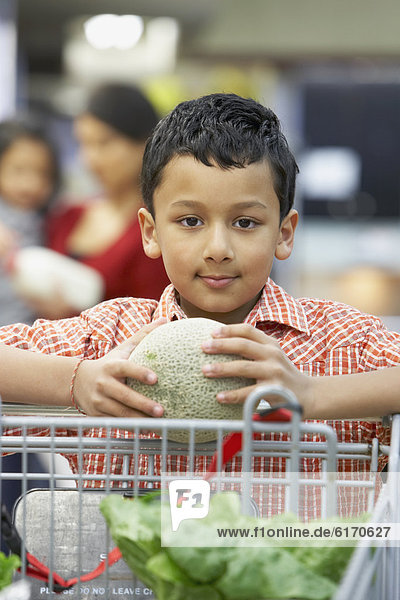 Indian boy holding fruit at grocery store