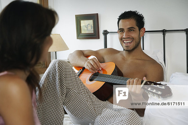 Hispanic man playing guitar for girlfriend