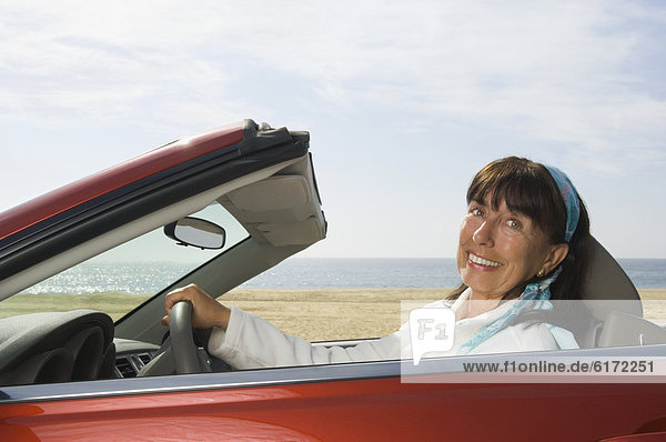 Senior Hispanic woman driving convertible car