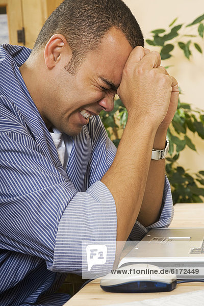 Frustrated Pacific Islander man next to laptop