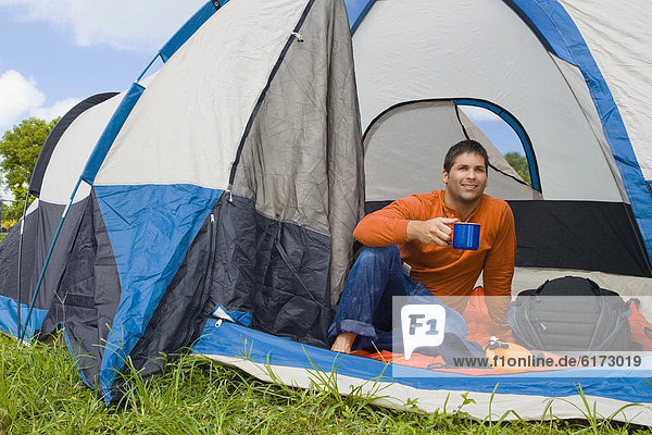 Hispanic man drinking coffee in tent