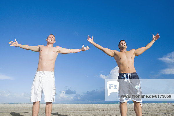 Multi-ethnic men with arms outstretched