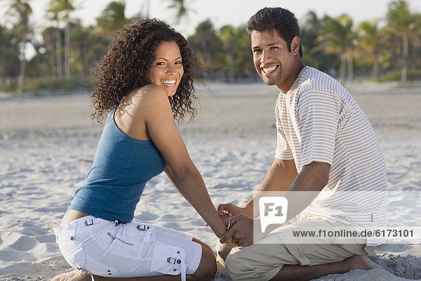Hispanic couple holding hands at beach