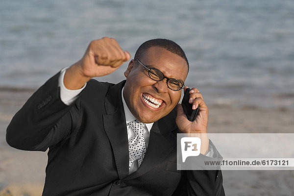 African businessman cheering on cell phone