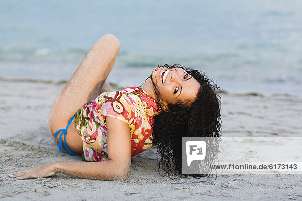 Hispanic woman laying on beach