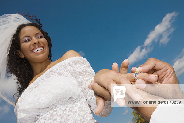 African groom putting ring on bride's finger