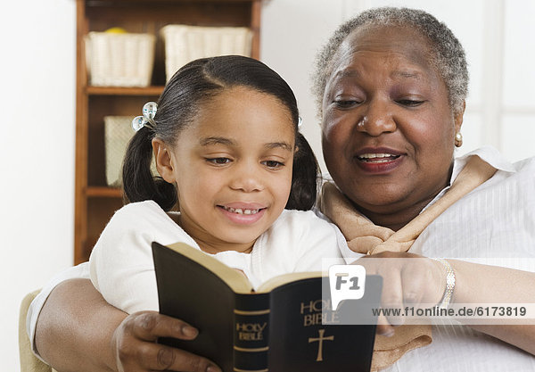 Senior woman reading the Bible to her granddaughter