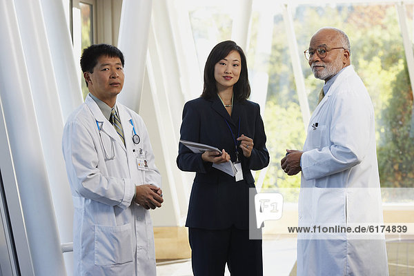 Two male doctors talking to Asian businesswoman