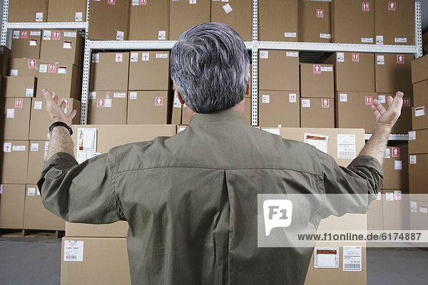 Businessman in warehouse looking at stacks of packages