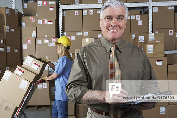 Businessman in warehouse with clipboard